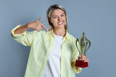 Photo of Happy winner with golden trophy cup on gray background,