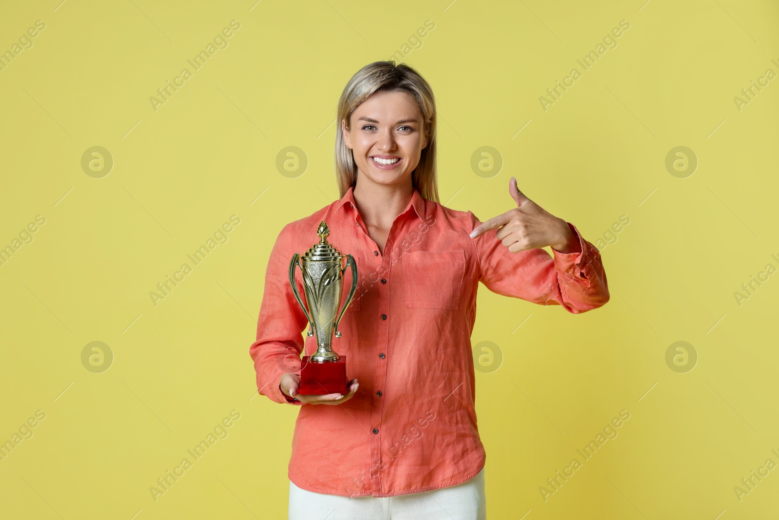 Photo of Happy winner with golden trophy cup on yellow background