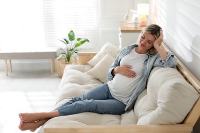 Portrait of beautiful pregnant woman on sofa at home