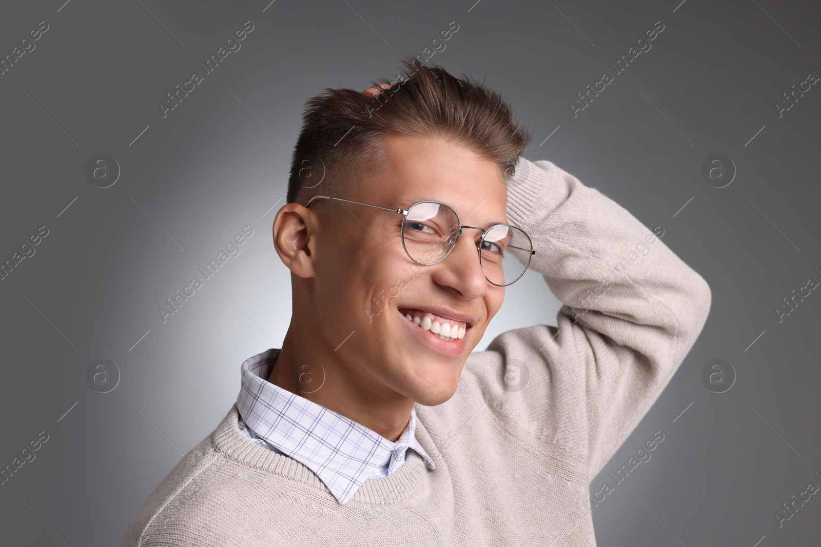 Photo of Handsome young man with stylish haircut on grey background