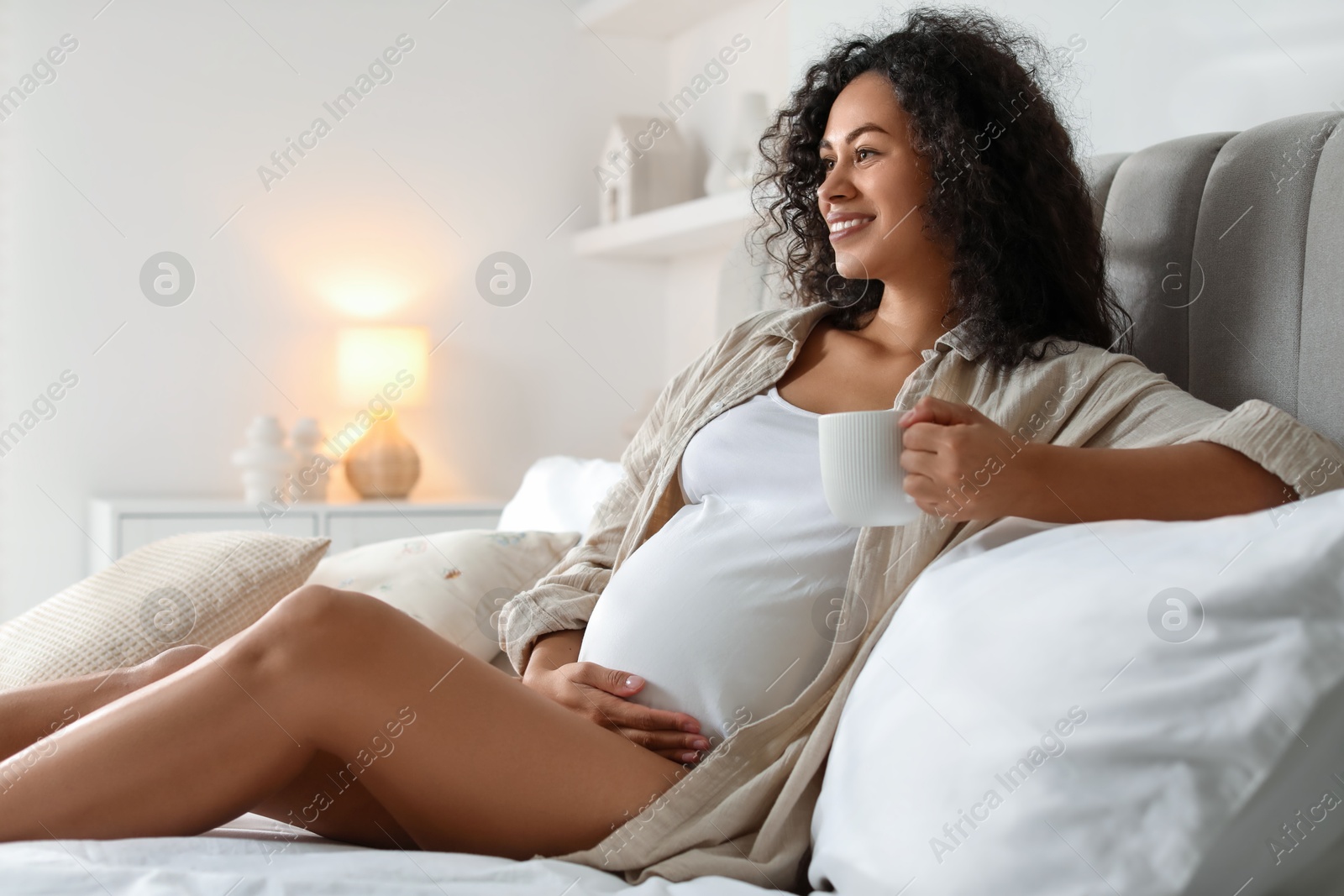 Photo of Portrait of beautiful pregnant with cup of drink on bed at home