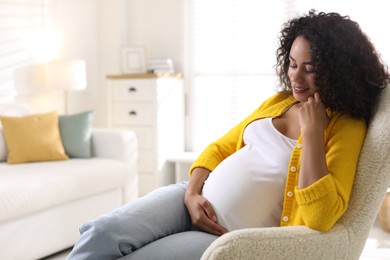 Portrait of beautiful pregnant woman in armchair at home