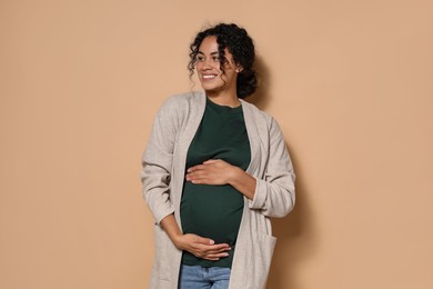 Portrait of beautiful pregnant woman on beige background