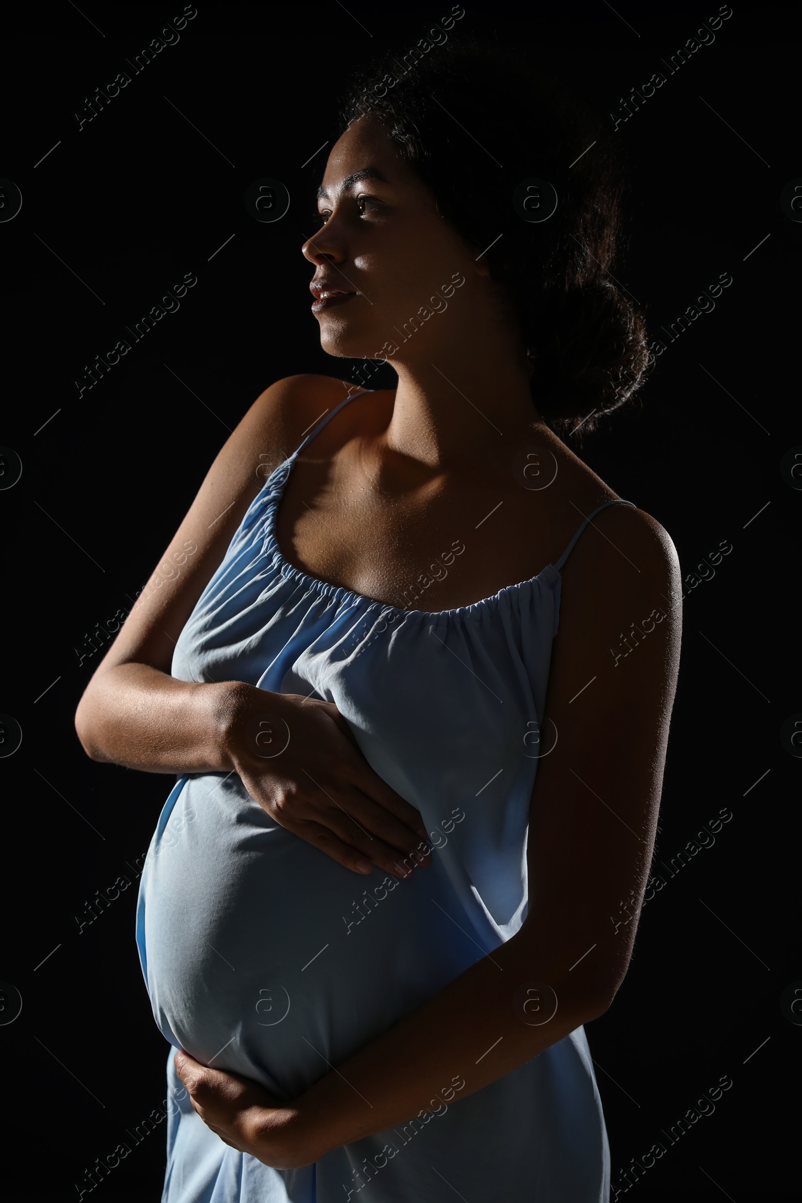 Photo of Portrait of beautiful pregnant woman on black background