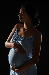 Portrait of beautiful pregnant woman on black background