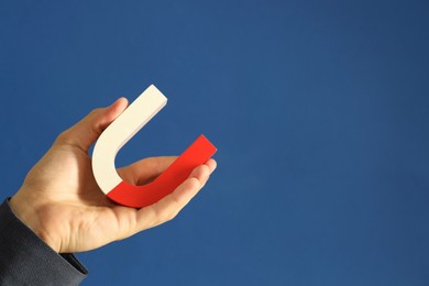 Photo of Man holding horseshoe magnet on blue background, closeup. Space for text