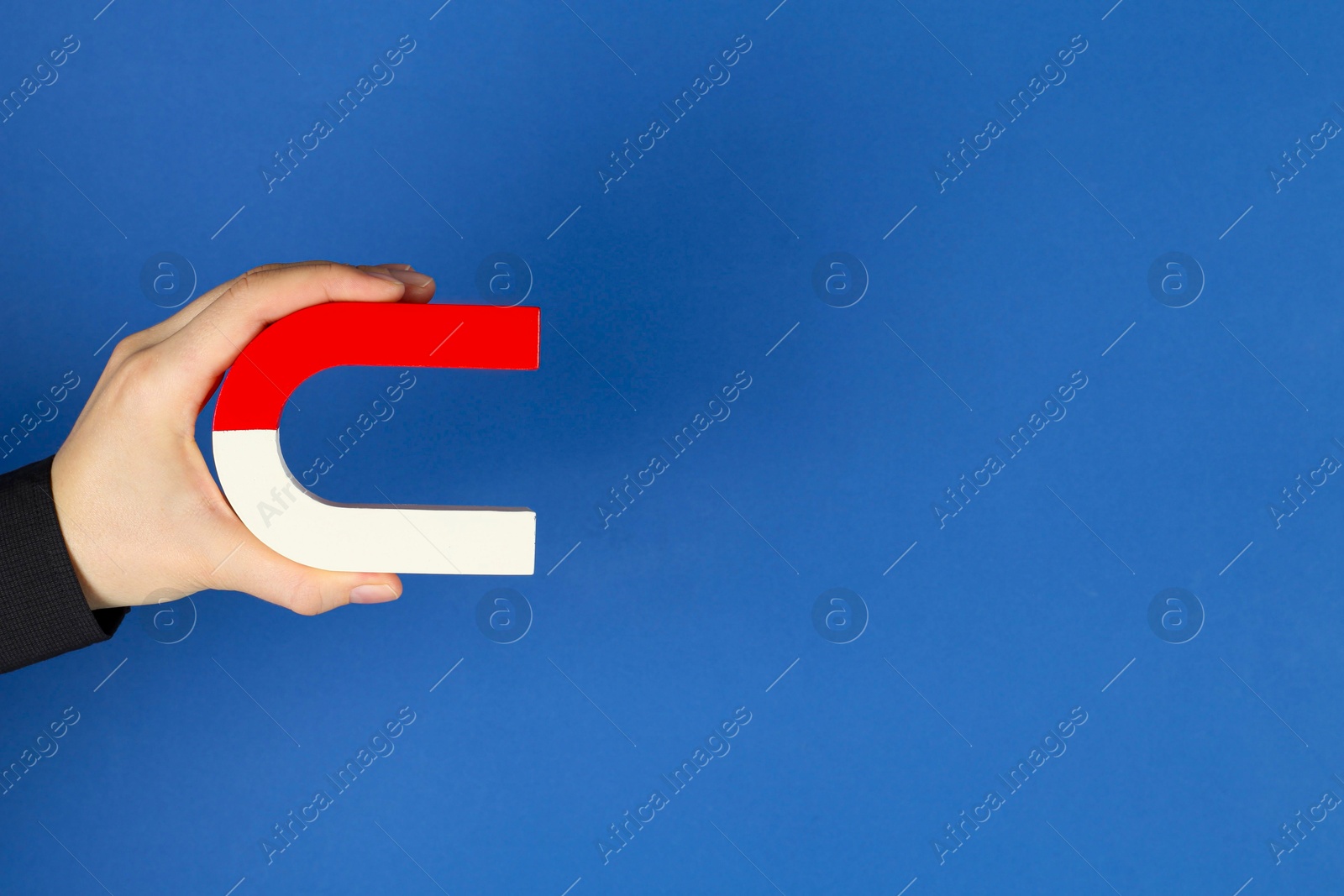 Photo of Woman with horseshoe magnet on blue background, closeup. Space for text