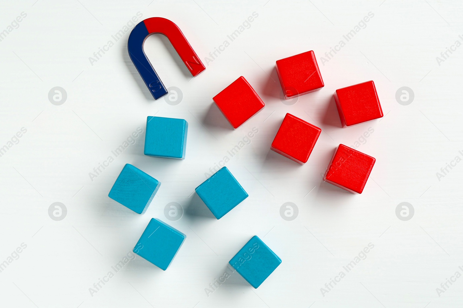 Photo of Magnet attracting colorful cubes on white background, flat lay