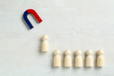 Photo of Magnet attracting human figure among other ones on white table, flat lay