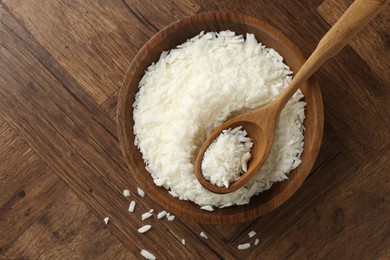 Photo of White soy wax flakes in bowl and spoon on wooden table, top view