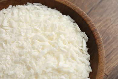 Photo of White soy wax flakes in bowl on wooden table, closeup