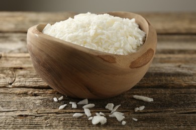 Photo of White soy wax flakes in bowl on wooden table, closeup