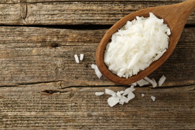 Photo of White soy wax flakes in spoon on wooden table, top view. Space for text