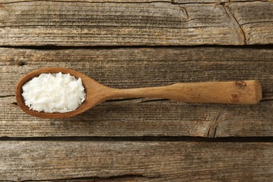 Photo of White soy wax flakes in spoon on wooden table, top view