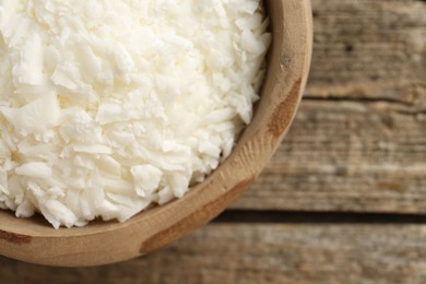 Photo of White soy wax flakes in bowl on wooden table, closeup