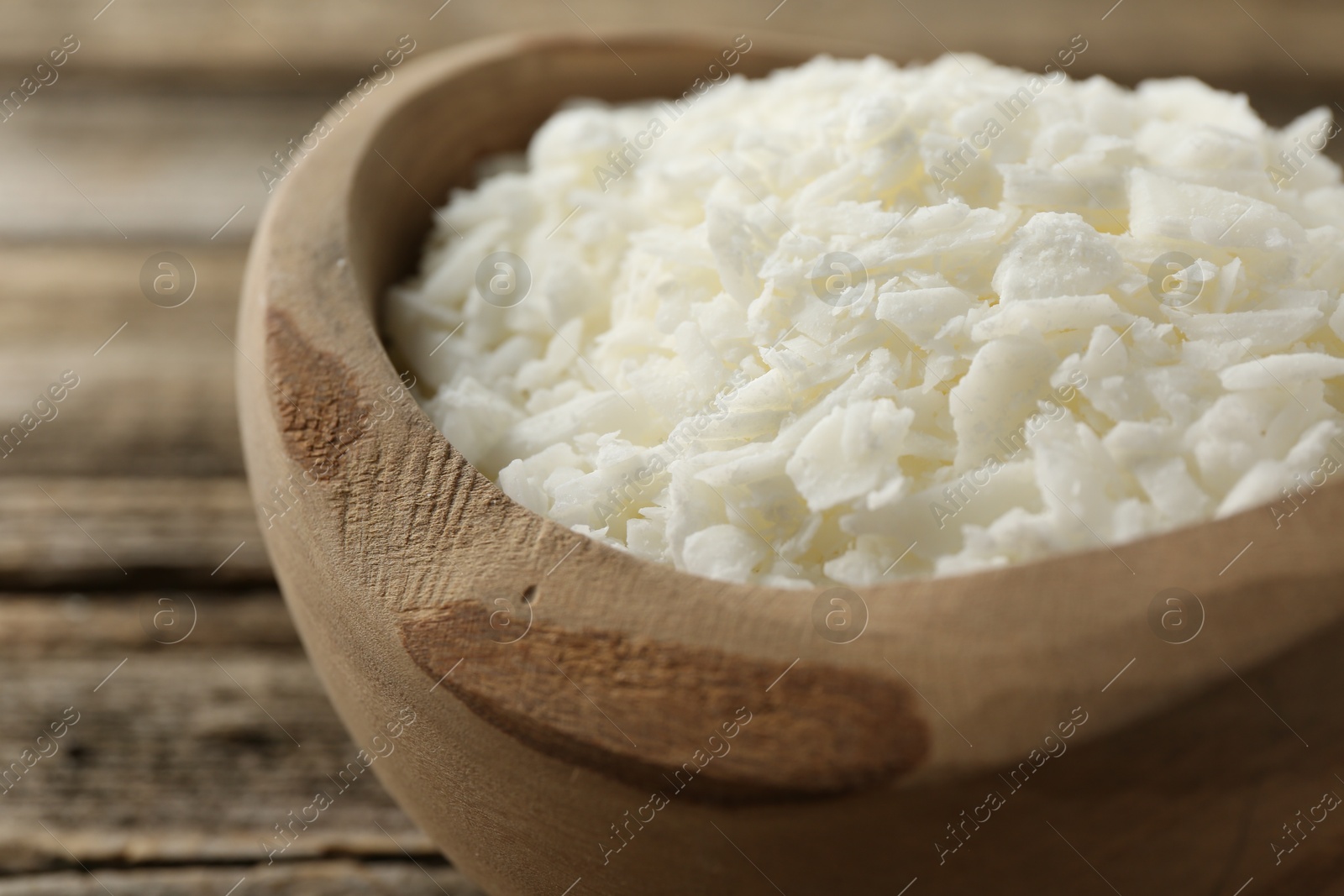 Photo of White soy wax flakes in bowl on table, closeup