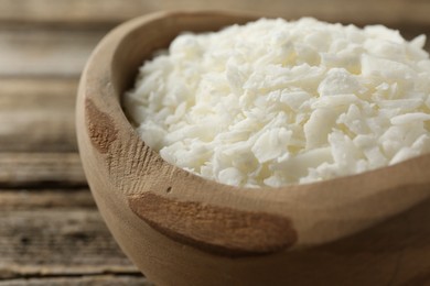 White soy wax flakes in bowl on table, closeup