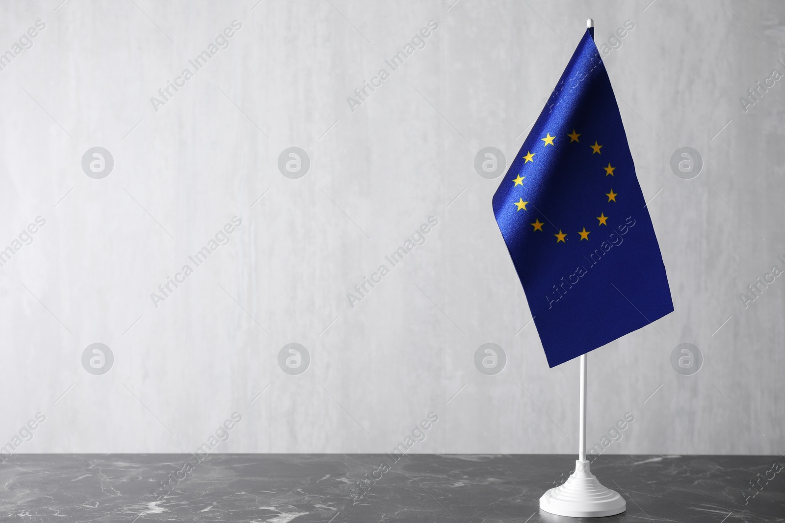 Photo of One flag of European Union on grey marble table. Space for text