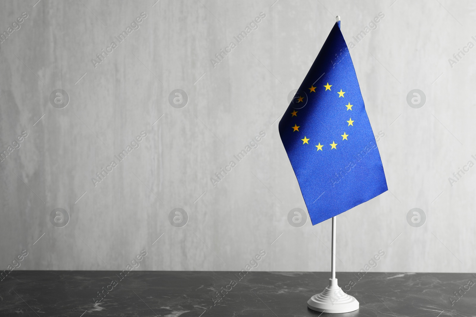 Photo of One flag of European Union on grey marble table. Space for text