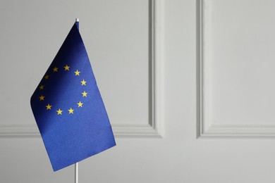 Photo of One flag of European Union near light grey wall. Space for text