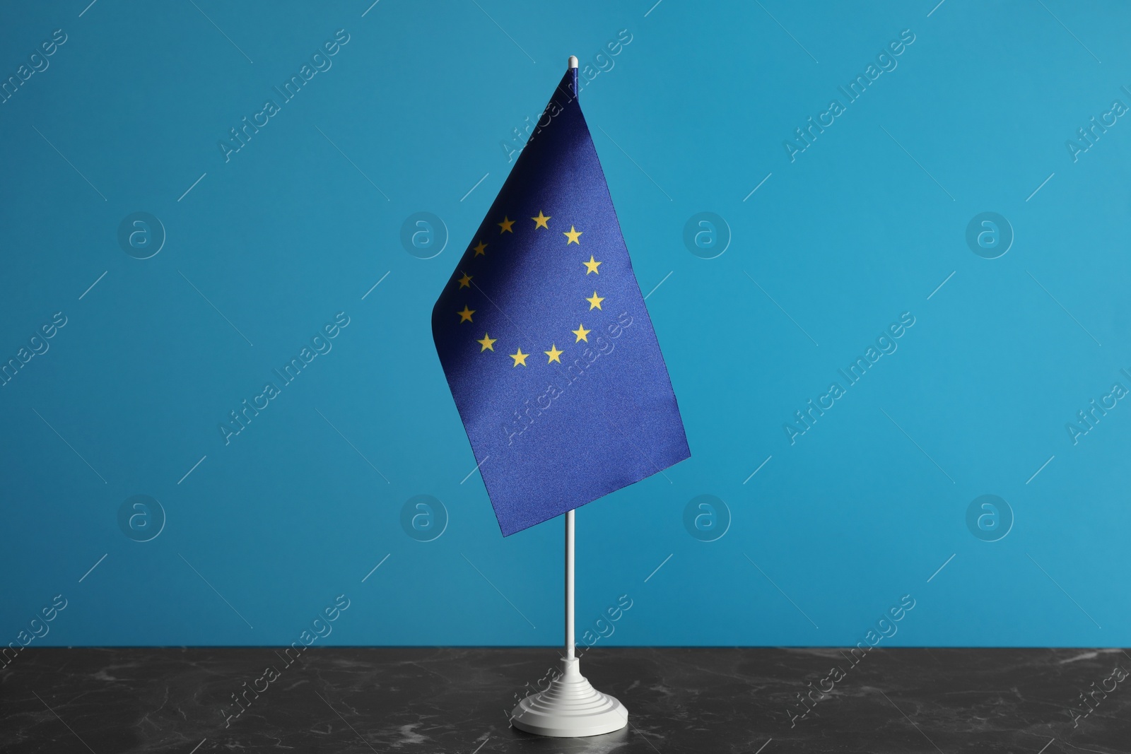 Photo of One flag of European Union on grey marble table against light blue background