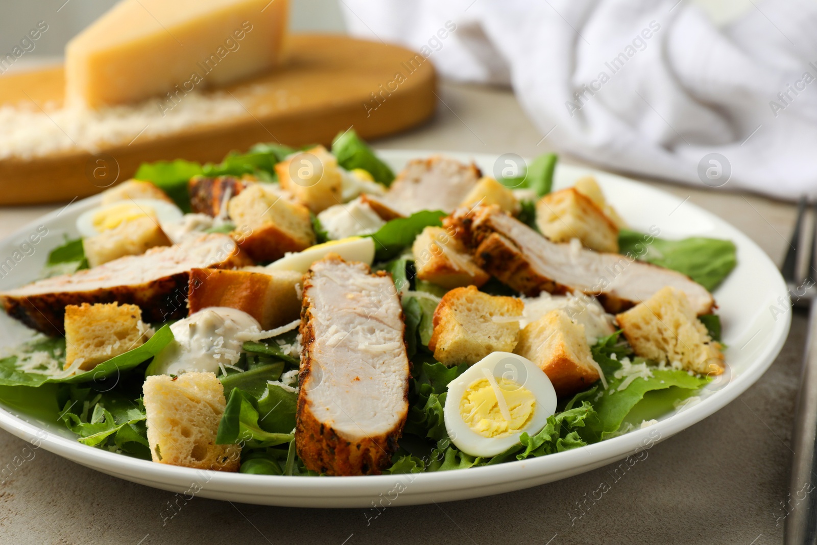 Photo of Tasty Caesar salad with chicken on light grey table, closeup