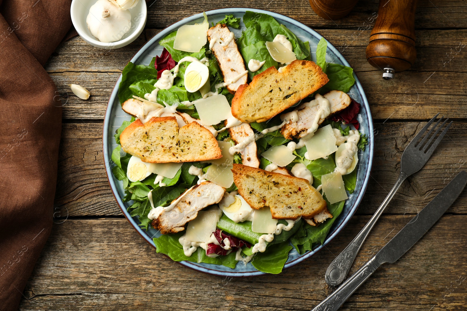 Photo of Tasty Caesar salad with chicken served on wooden table, flat lay