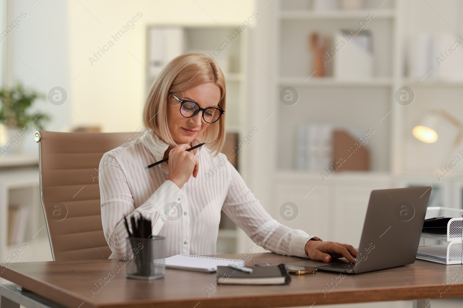 Photo of Middle aged woman working at table in office