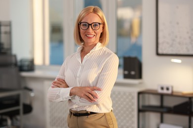 Photo of Portrait of smiling middle aged woman with crossed arms in office