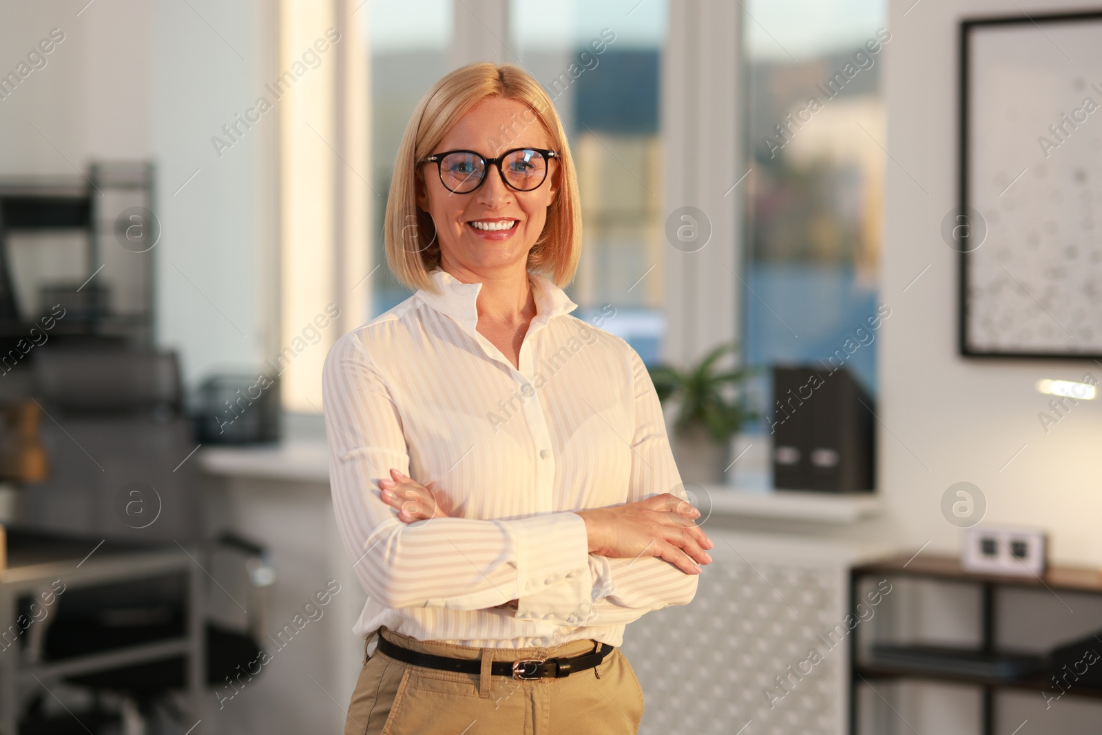 Photo of Portrait of smiling middle aged woman with crossed arms in office