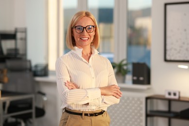 Portrait of smiling middle aged woman with crossed arms in office