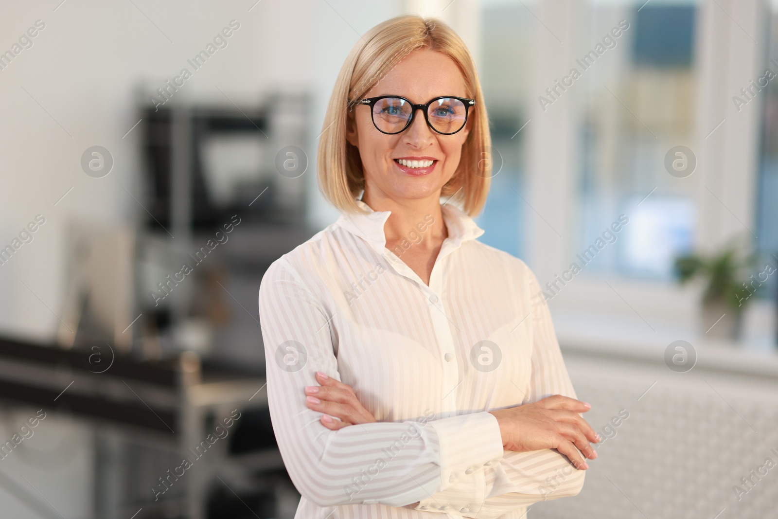 Photo of Portrait of smiling middle aged woman with crossed arms in office