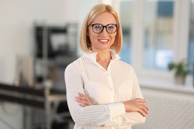 Portrait of smiling middle aged woman with crossed arms in office