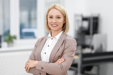 Photo of Portrait of smiling middle aged woman with crossed arms in office