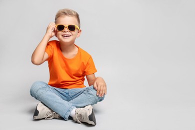 Photo of Little boy with sunglasses on light grey background, space for text