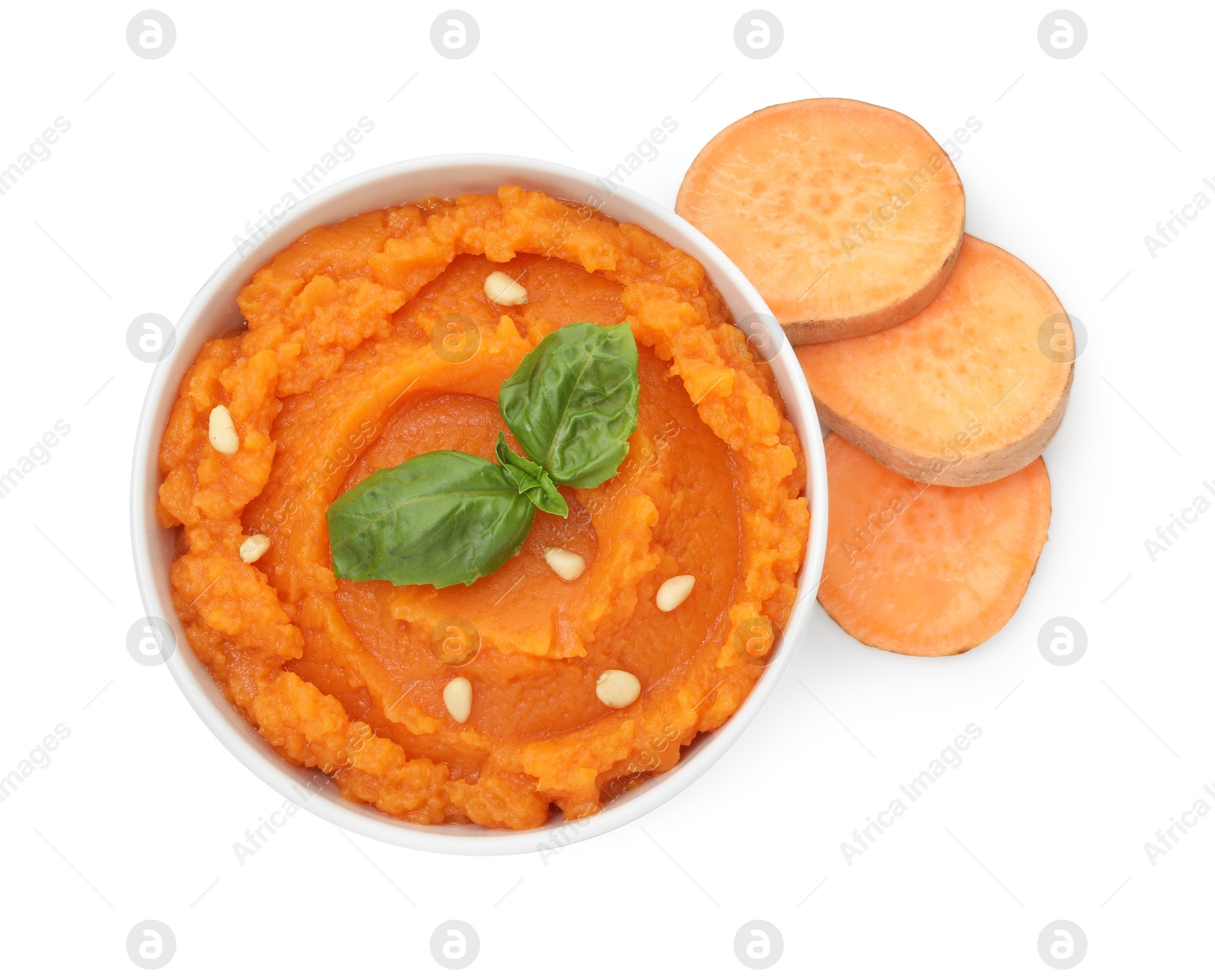 Photo of Tasty mashed sweet potato with basil, seeds in bowl and fresh cut vegetable isolated on white, top view