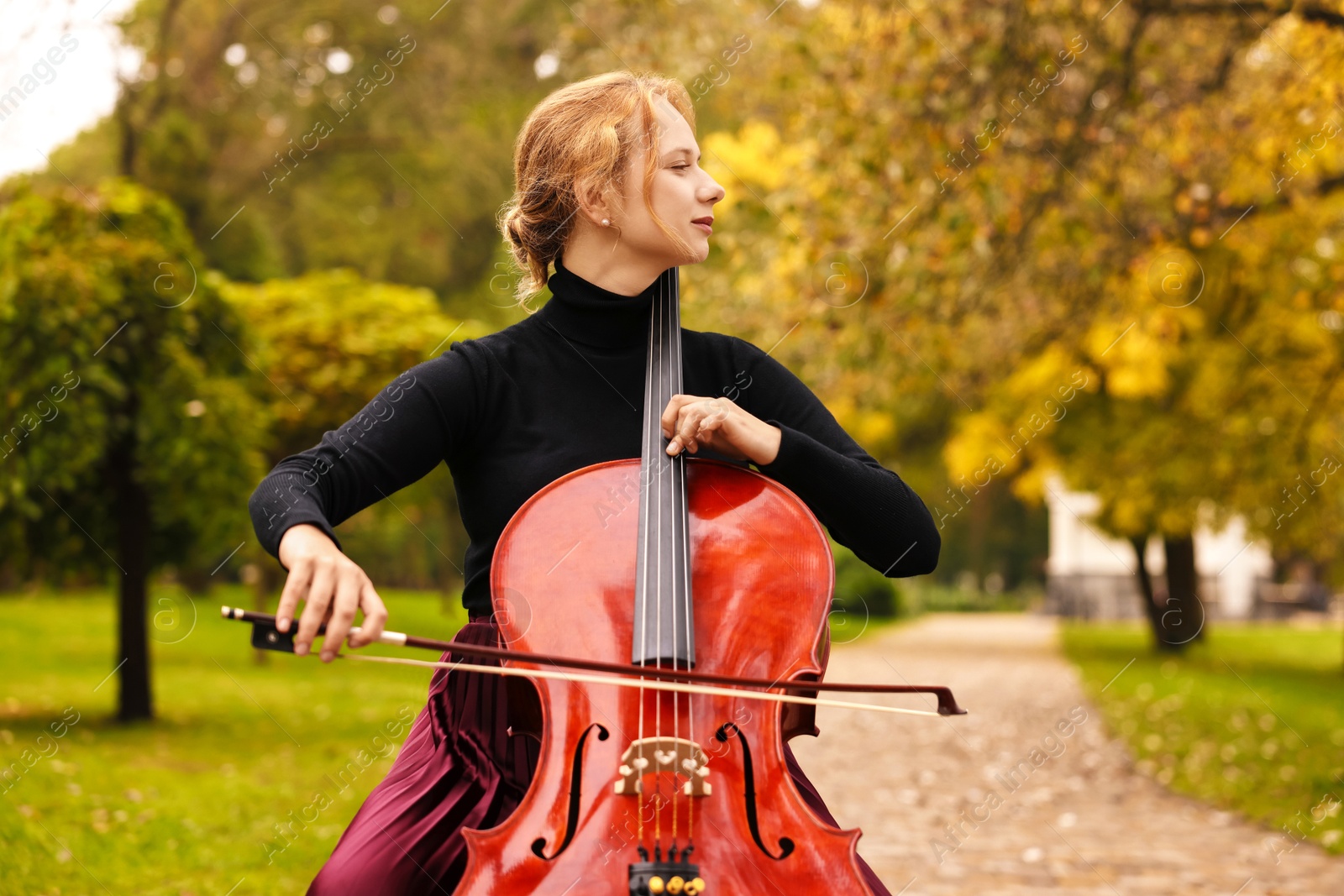 Photo of Beautiful young woman playing cello in park