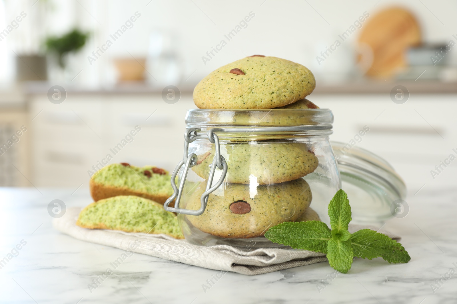 Photo of Delicious mint chocolate chip cookies in jar on white marble table, closeup