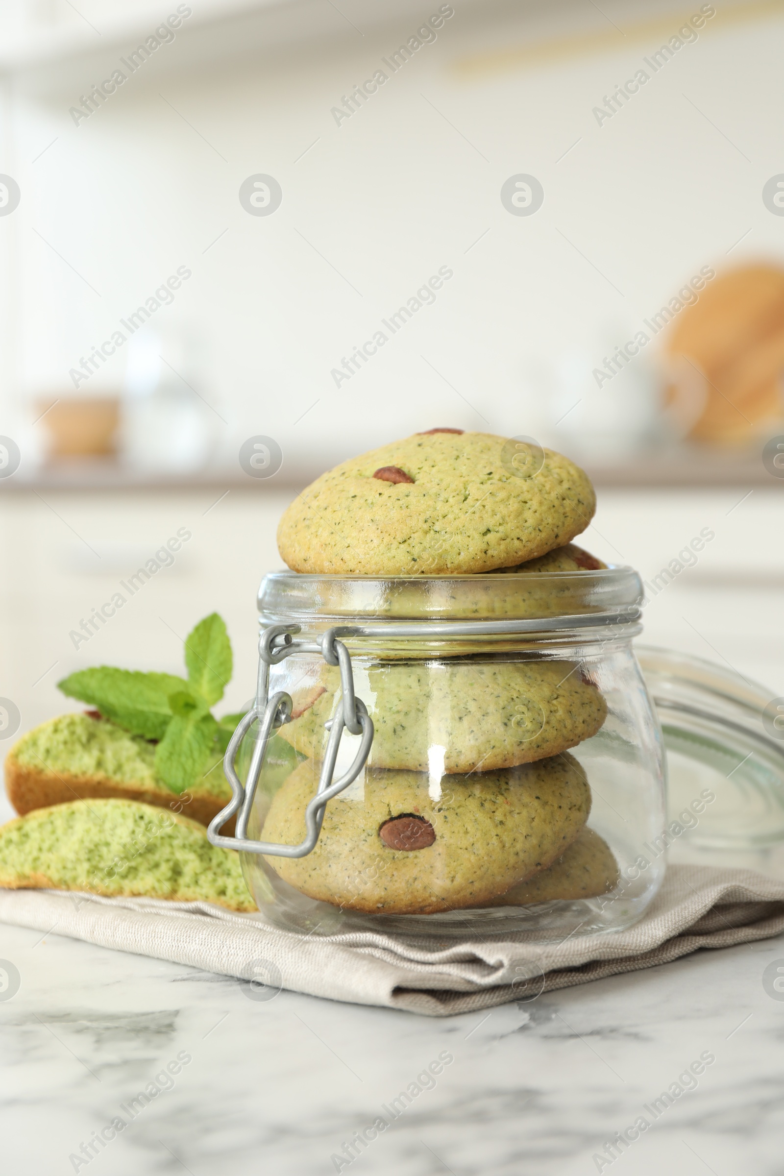 Photo of Delicious mint chocolate chip cookies in jar on white marble table