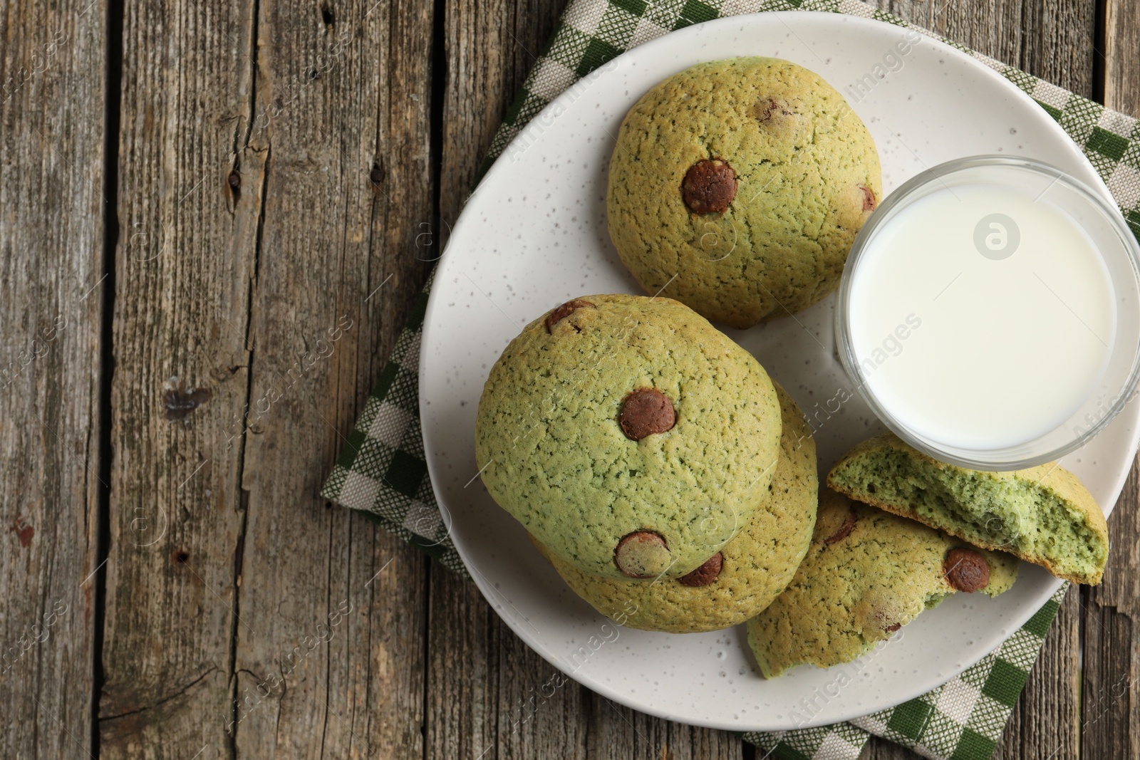 Photo of Delicious mint chocolate chip cookies and milk on wooden table, top view. Space for text