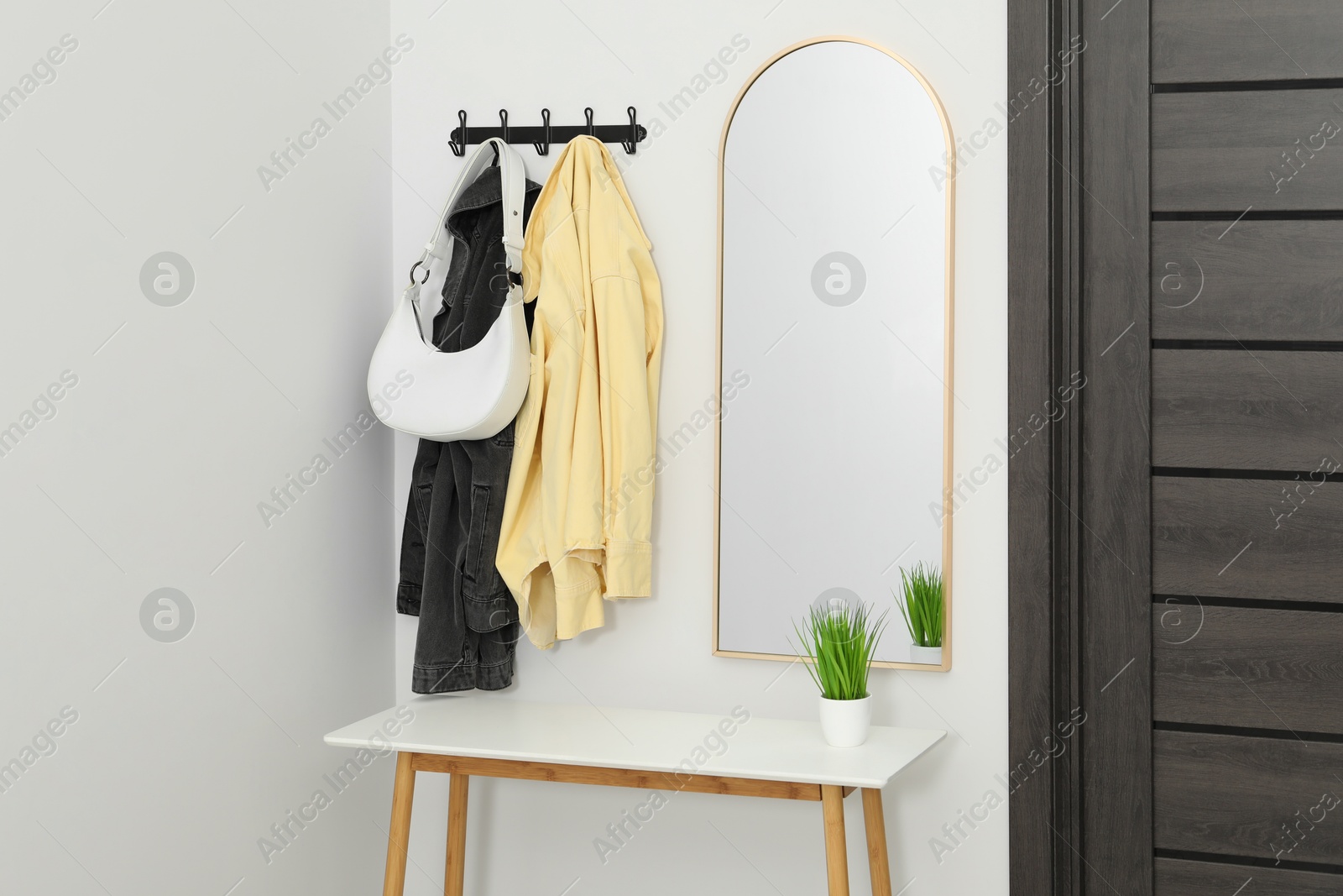 Photo of Mirror, rack with clothes and shoe storage bench in hallway. Interior design