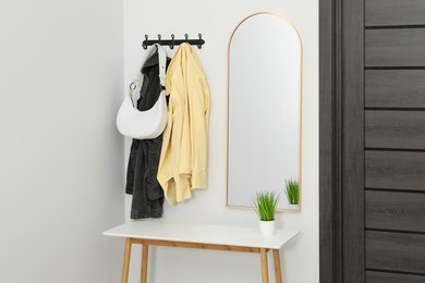 Mirror, rack with clothes and shoe storage bench in hallway. Interior design