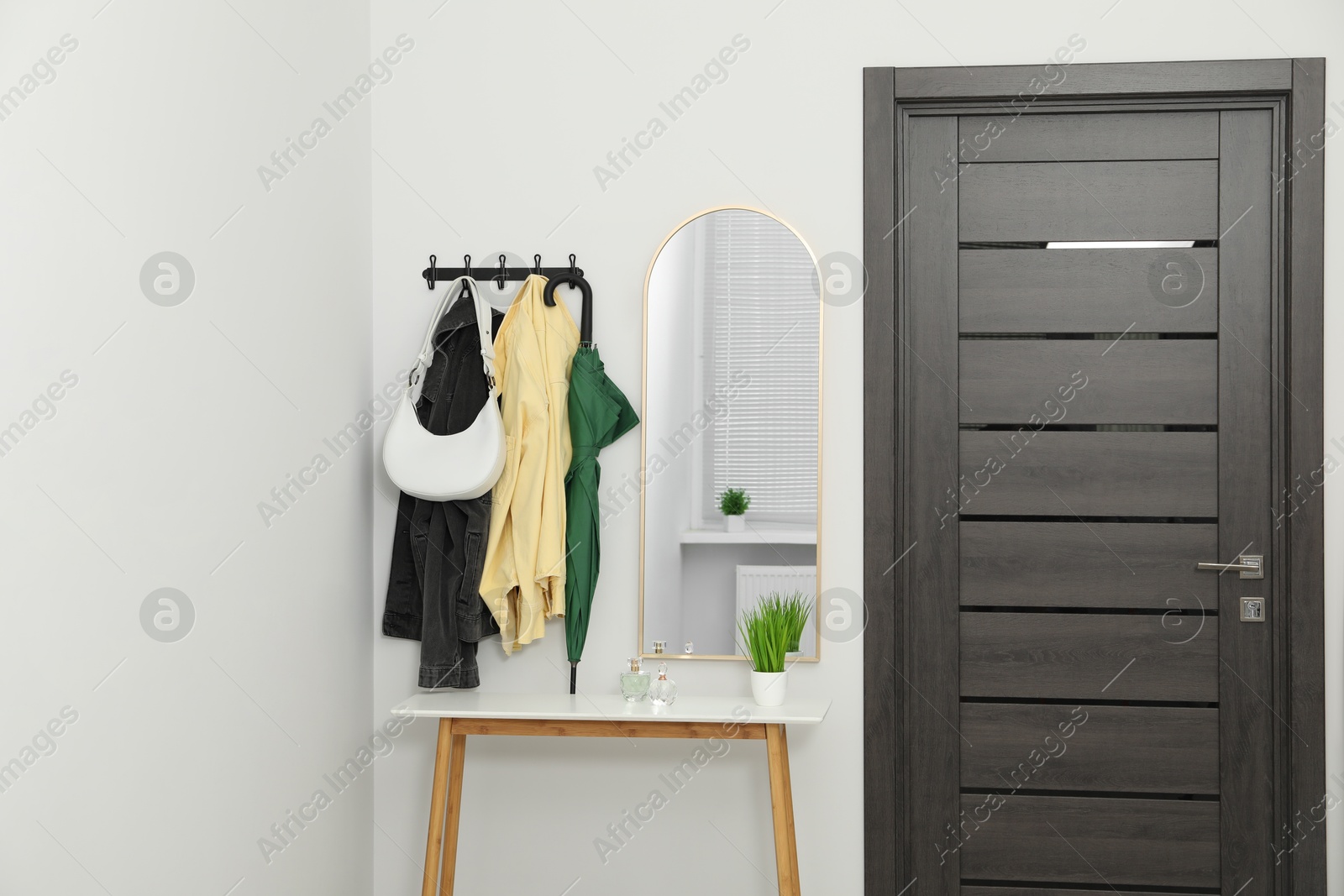 Photo of Mirror, rack with clothes and shoe storage bench in hallway. Interior design