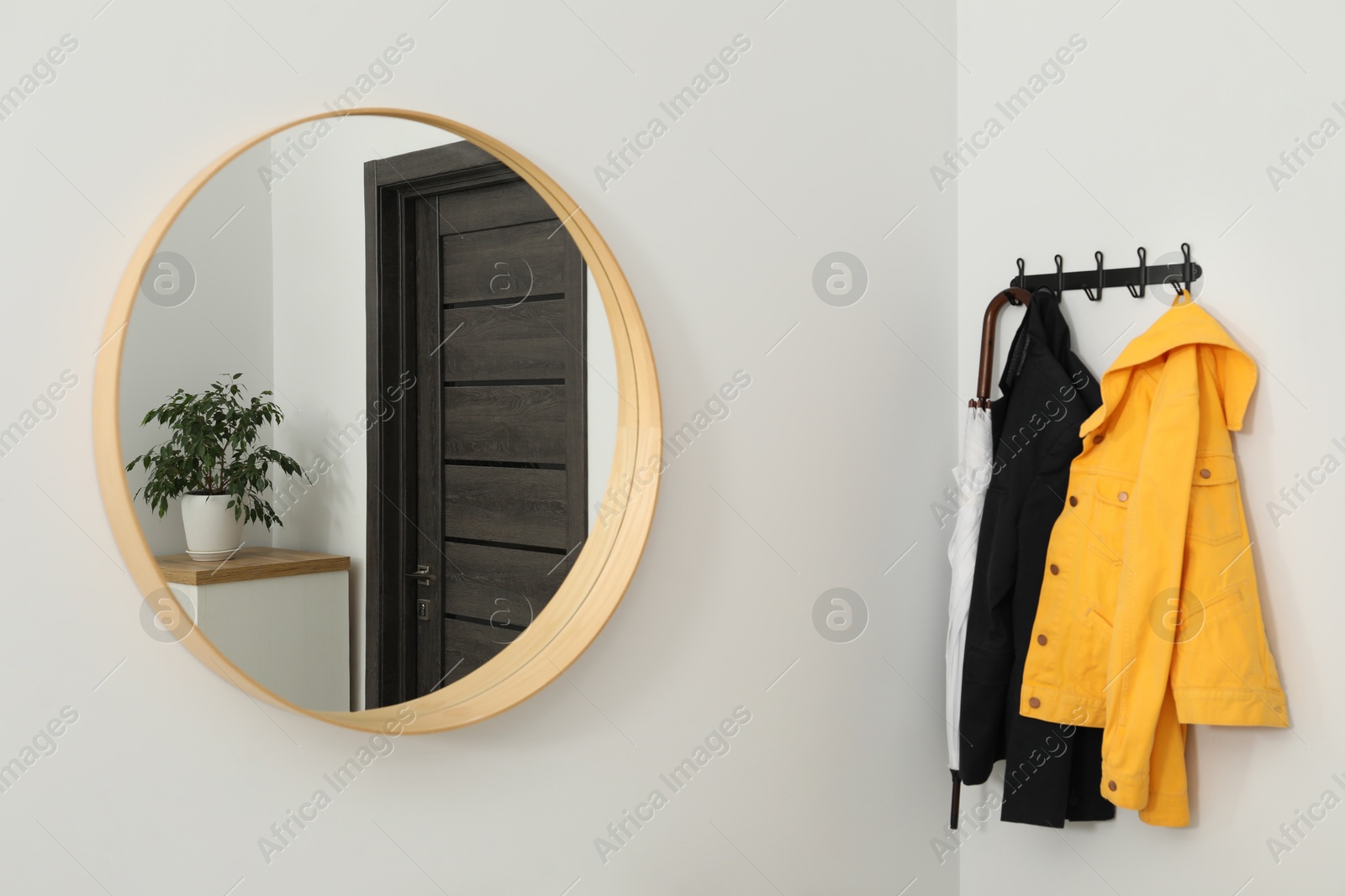 Photo of Mirror and rack with clothes in hallway. Interior design