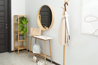 Clothing rack, mirror, houseplant, storage bench and shelving unit in hallway