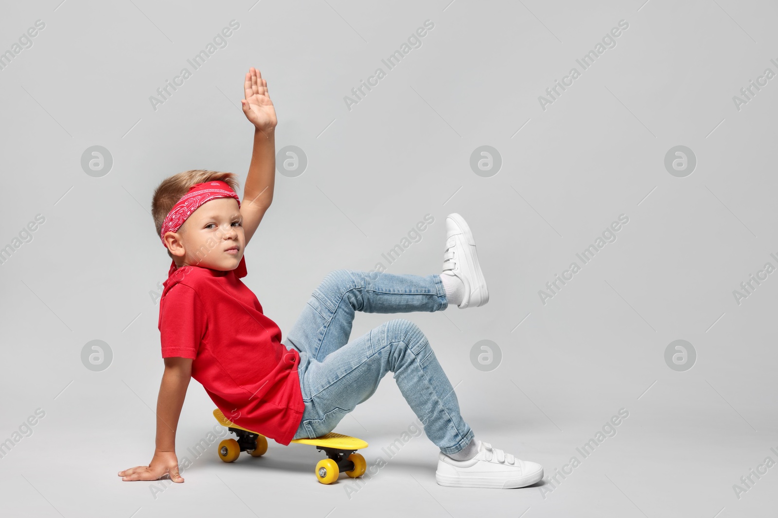 Photo of Little boy with skateboard on light grey background, space for text