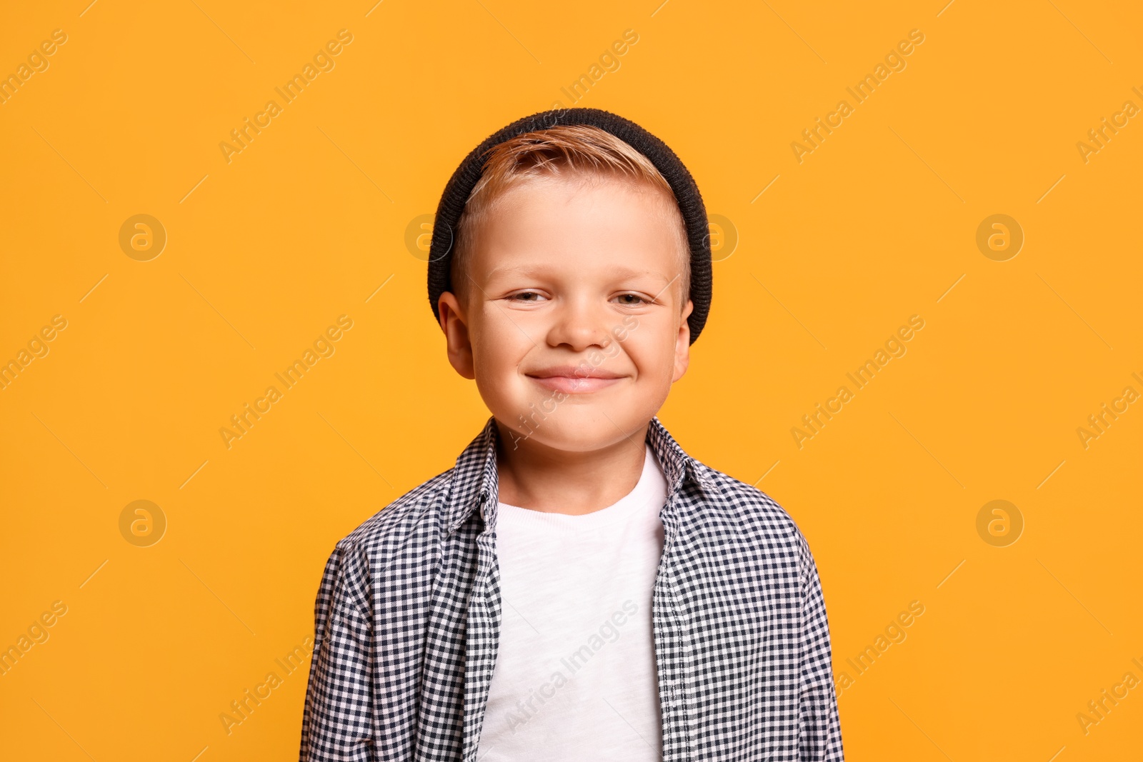 Photo of Portrait of little boy with stylish clothes on orange background