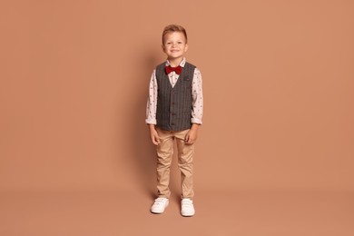 Photo of Full length portrait of little boy with stylish clothes on brown background