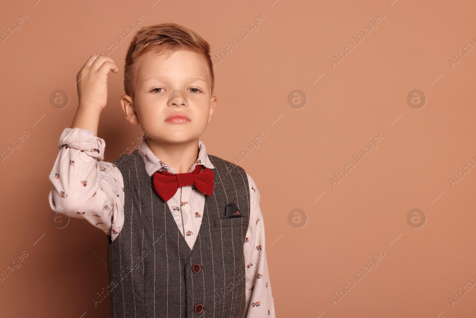 Photo of Portrait of little boy with stylish clothes on brown background, space for text