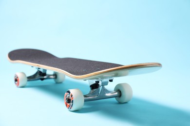 Photo of One skateboard on light blue background, closeup. Sports equipment